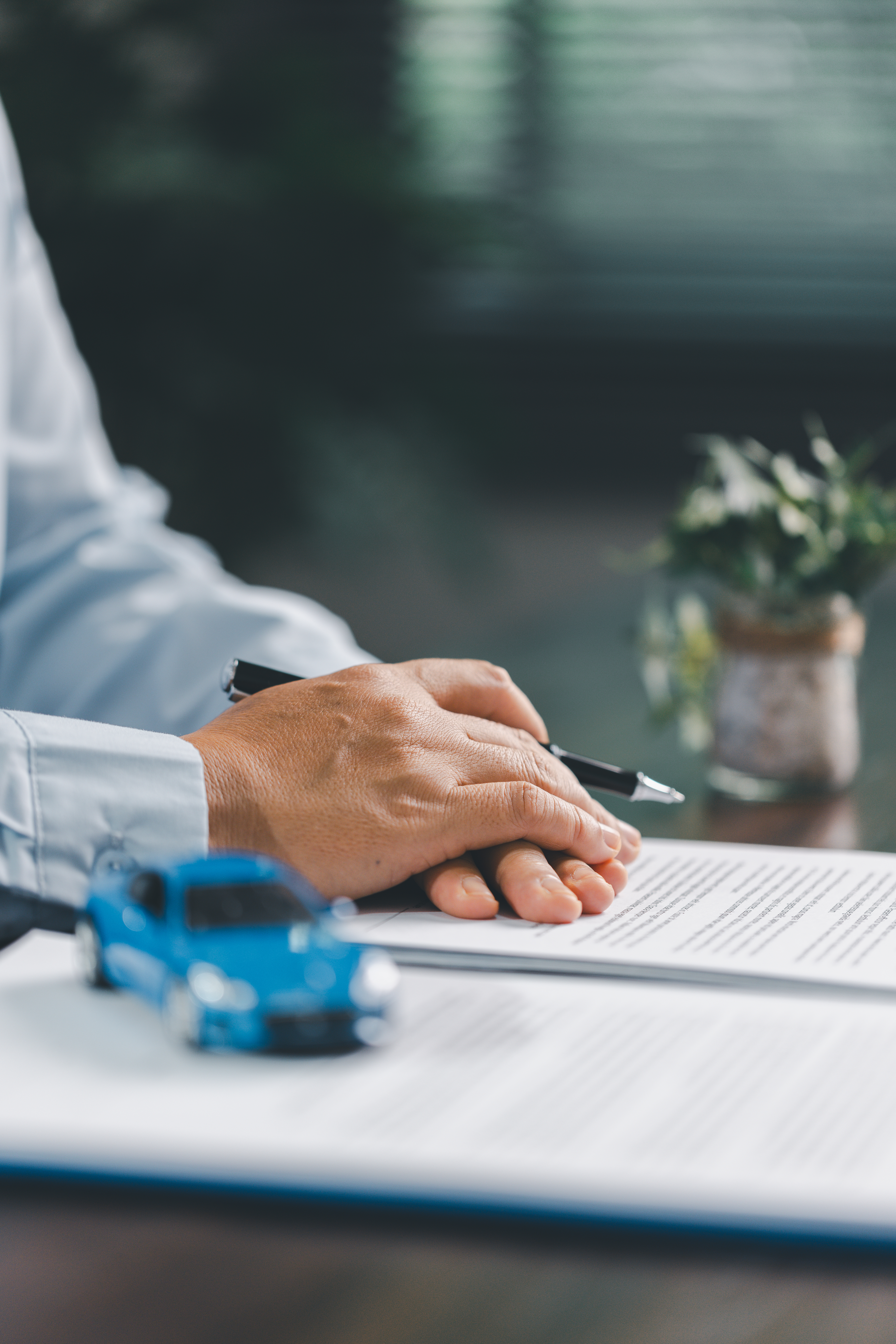 Business office, woman employee finalizes deal with client, handing over car key after signing contract and reviewing insurance and loan documents for sale or rent of vehicle at table.