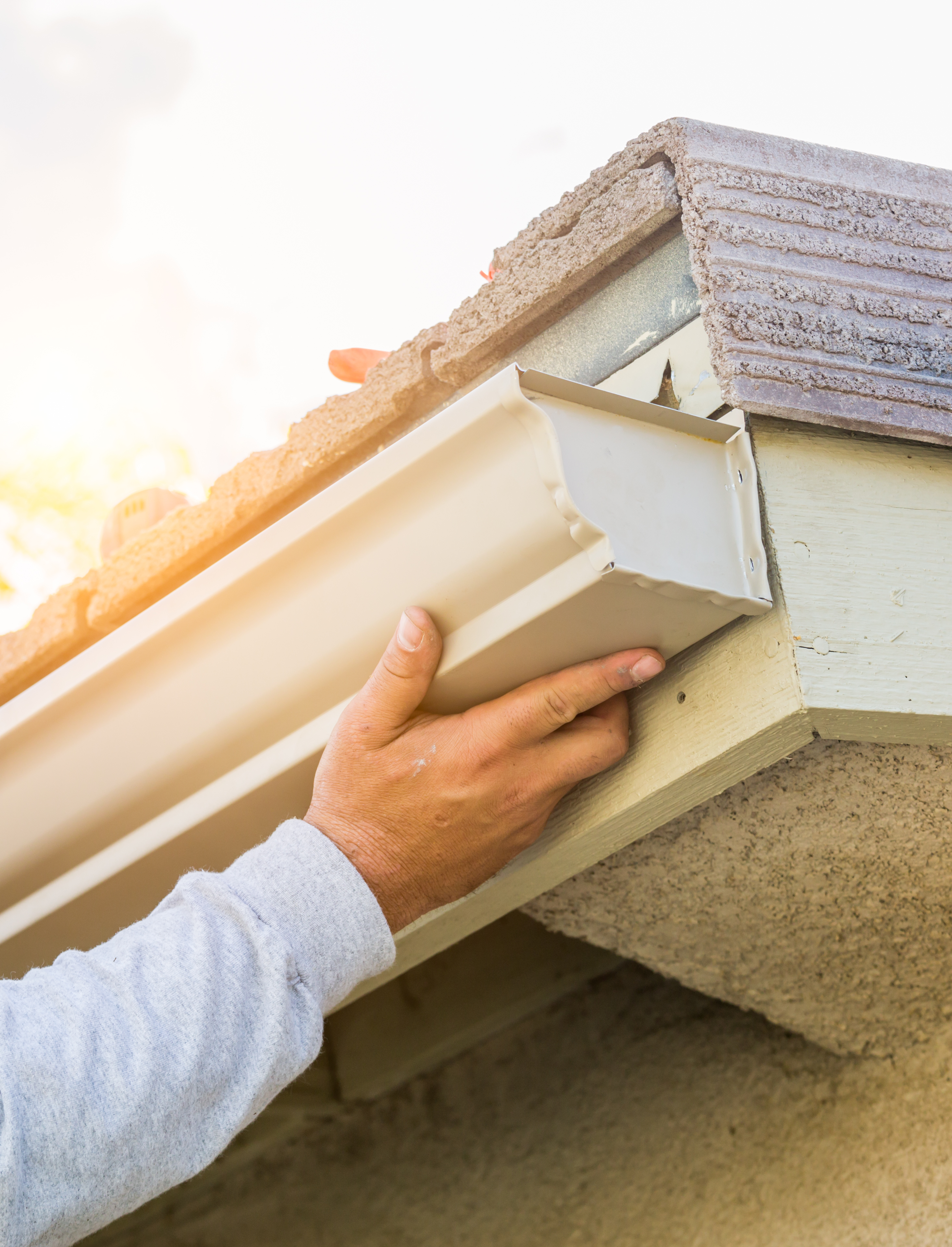 Worker Attaching Aluminum Rain Gutter to Fascia of House.Worker Attaching Aluminum Rain Gutter to Fascia of House.